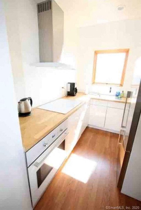 A kitchen with white appliances and wooden floors.