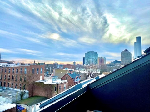 A cityscape with a mix of modern and older buildings under a partly cloudy sky.