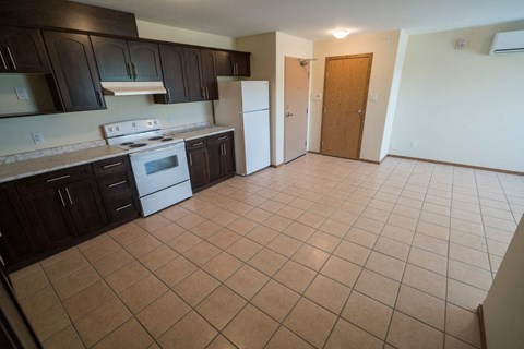 an empty kitchen with a white stove and refrigerator