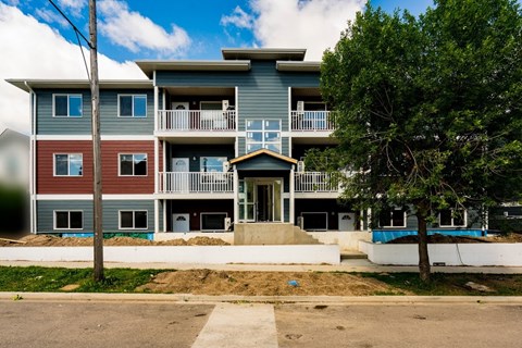 a blue apartment building with a tree in front of it