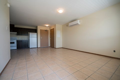 an empty kitchen and living room with tile flooring and white appliances