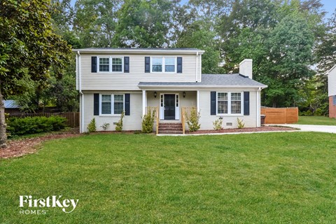 a white house with blue shutters and a green lawn