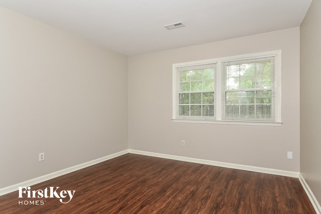 the living room of a home with wood flooring and two windows