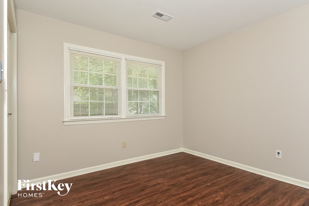 a bedroom with a hard wood floor and two windows
