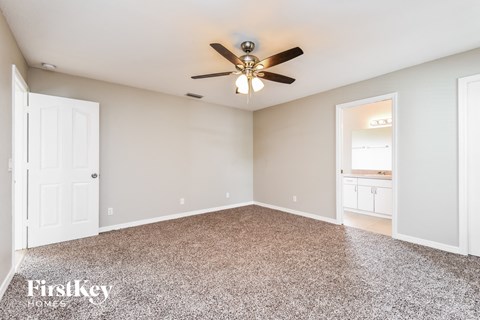 the master bedroom is spacious and clean with a ceiling fan