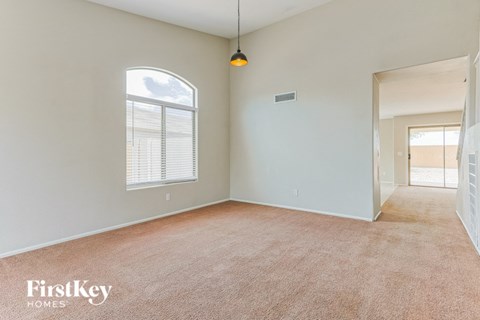 A spacious room with a carpeted floor and a window with blinds.
