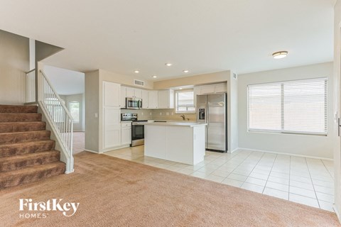 A spacious kitchen and living room with a staircase on the left side.