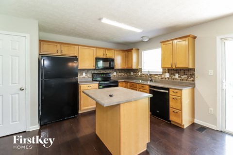A kitchen with wooden cabinets and a black fridge.
