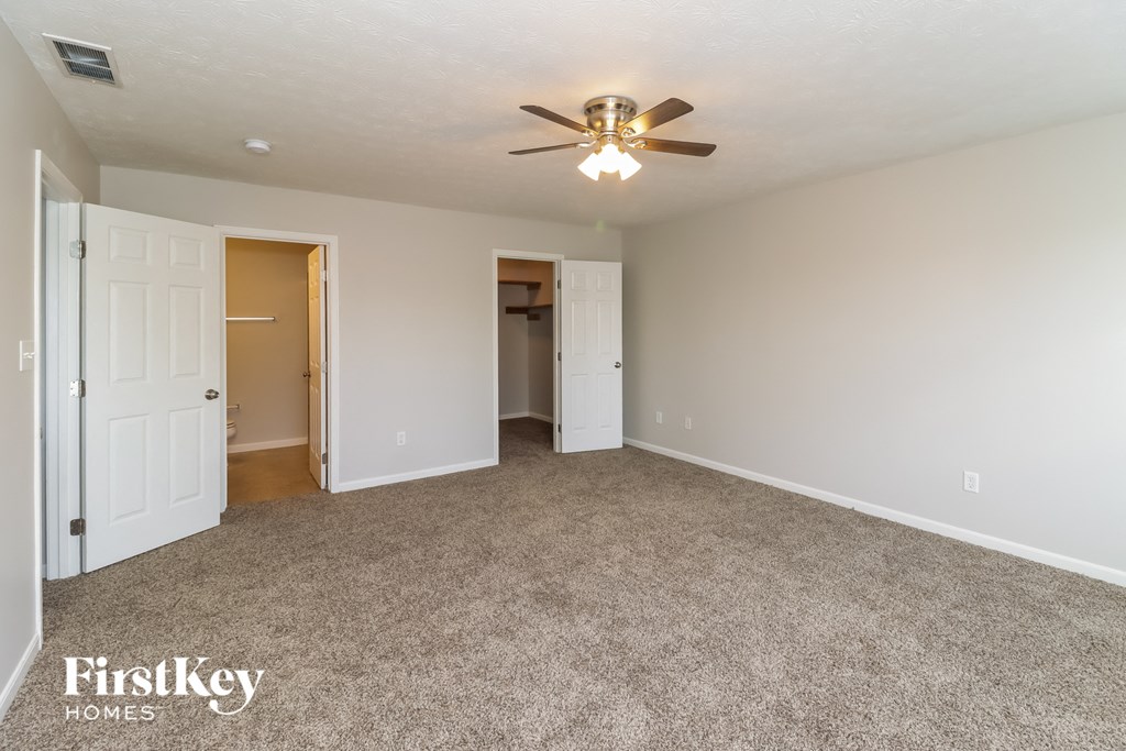 A spacious room with a ceiling fan and carpeted floor.