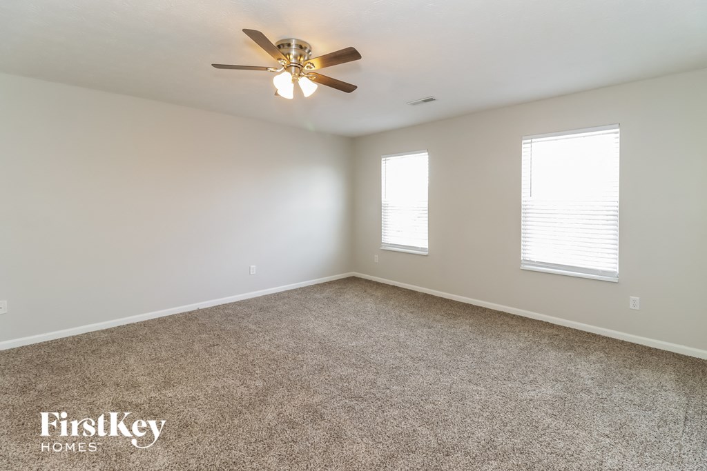 A room with a ceiling fan and carpeted floor.