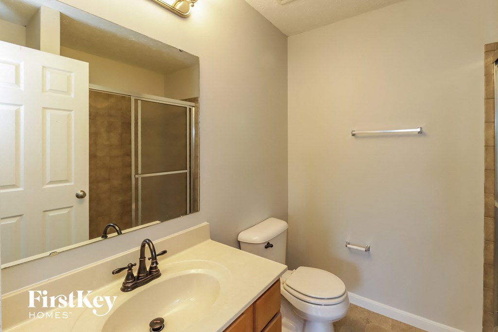 A bathroom with a toilet, sink, and mirror.