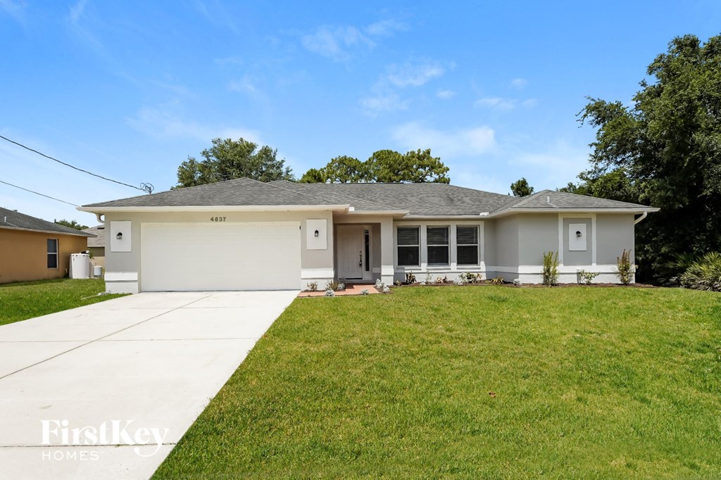 A house with a garage and a driveway in front of it.