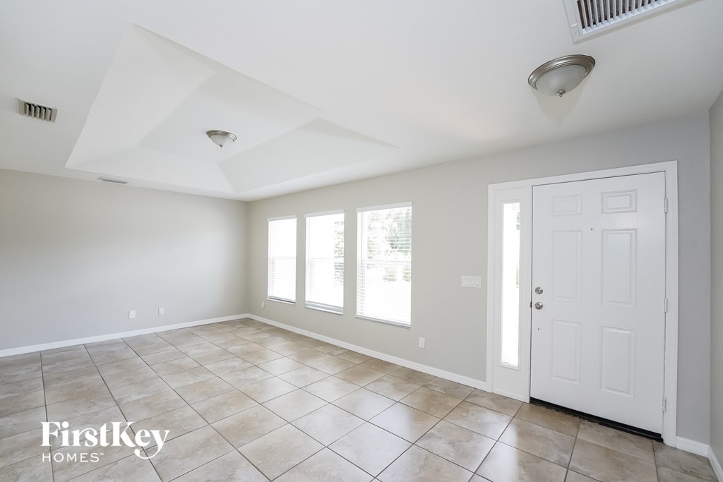 A spacious room with a white door and a window with blinds.