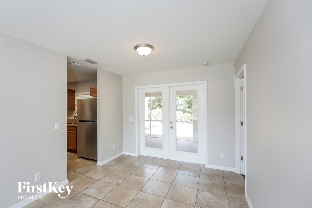A white room with a refrigerator and a door leading outside.