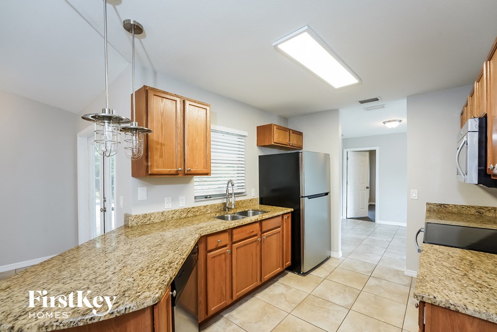 A kitchen with granite countertops and wooden cabinets.