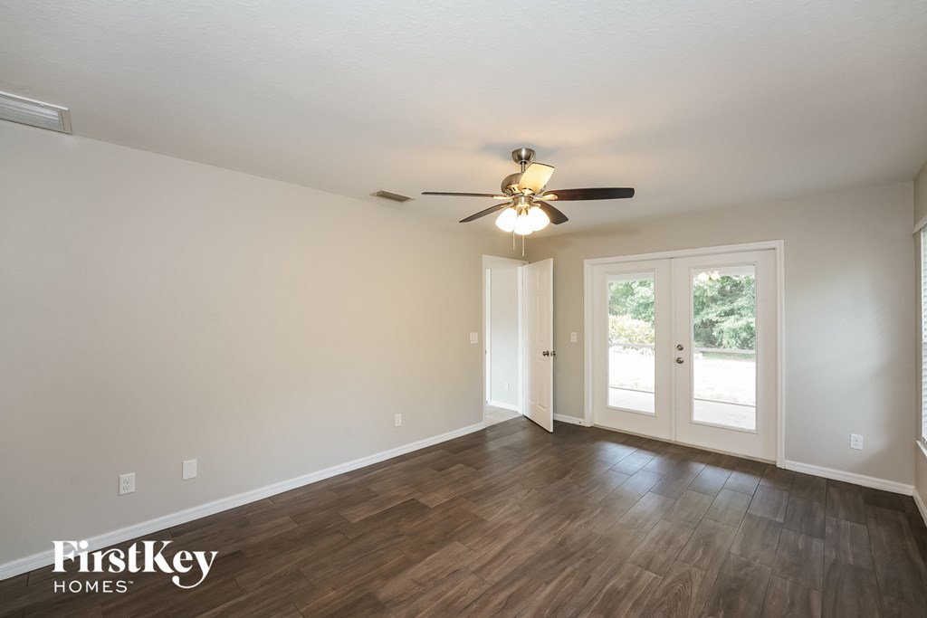 A spacious room with a ceiling fan and wooden flooring.