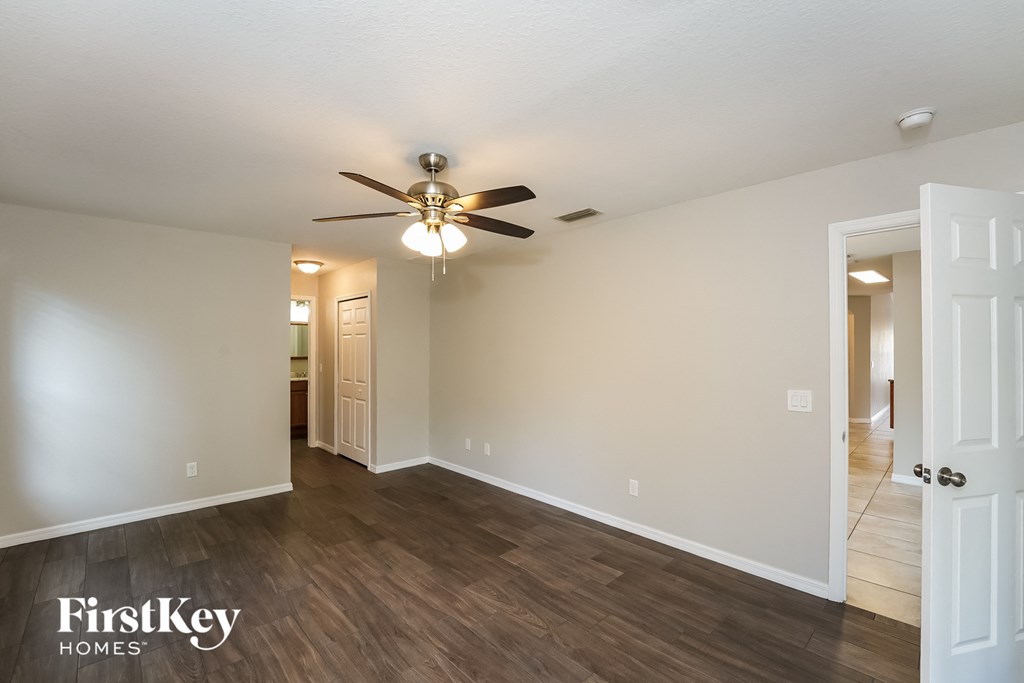 A room with a ceiling fan and wooden flooring.