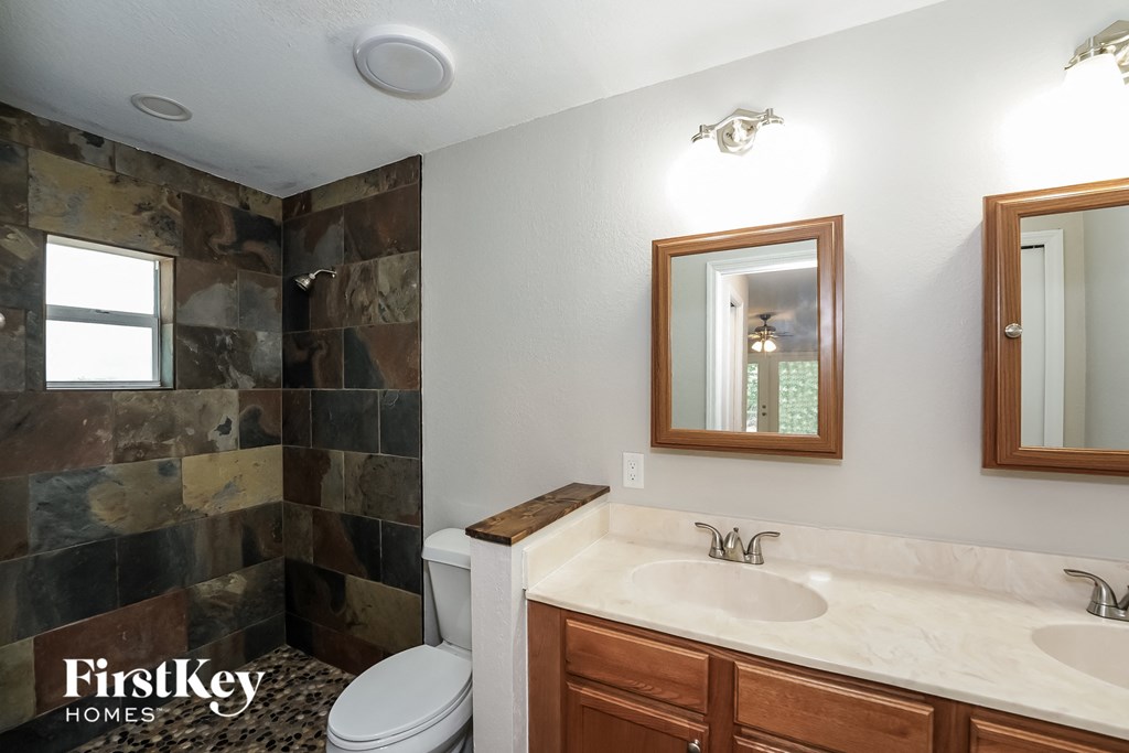 A bathroom with a toilet, sink, and mirror.