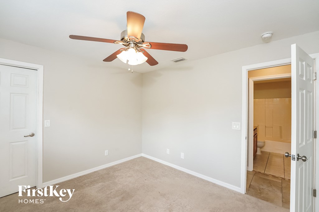 A room with a ceiling fan and a carpeted floor.