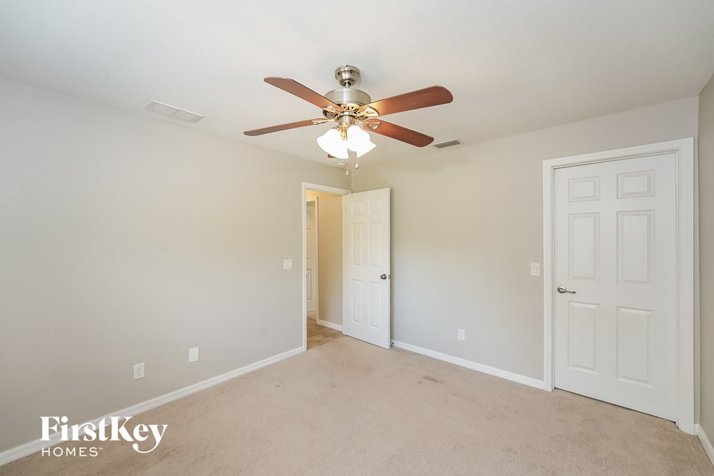 A spacious room with a ceiling fan and two doors.