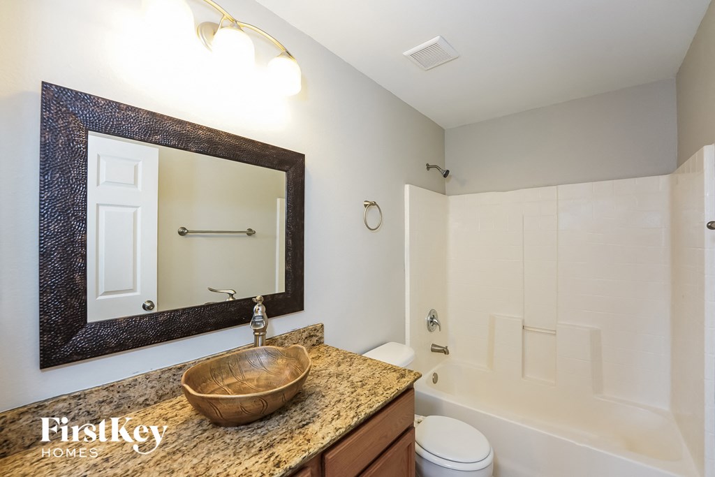 A bathroom with a granite countertop and a mirror above it.