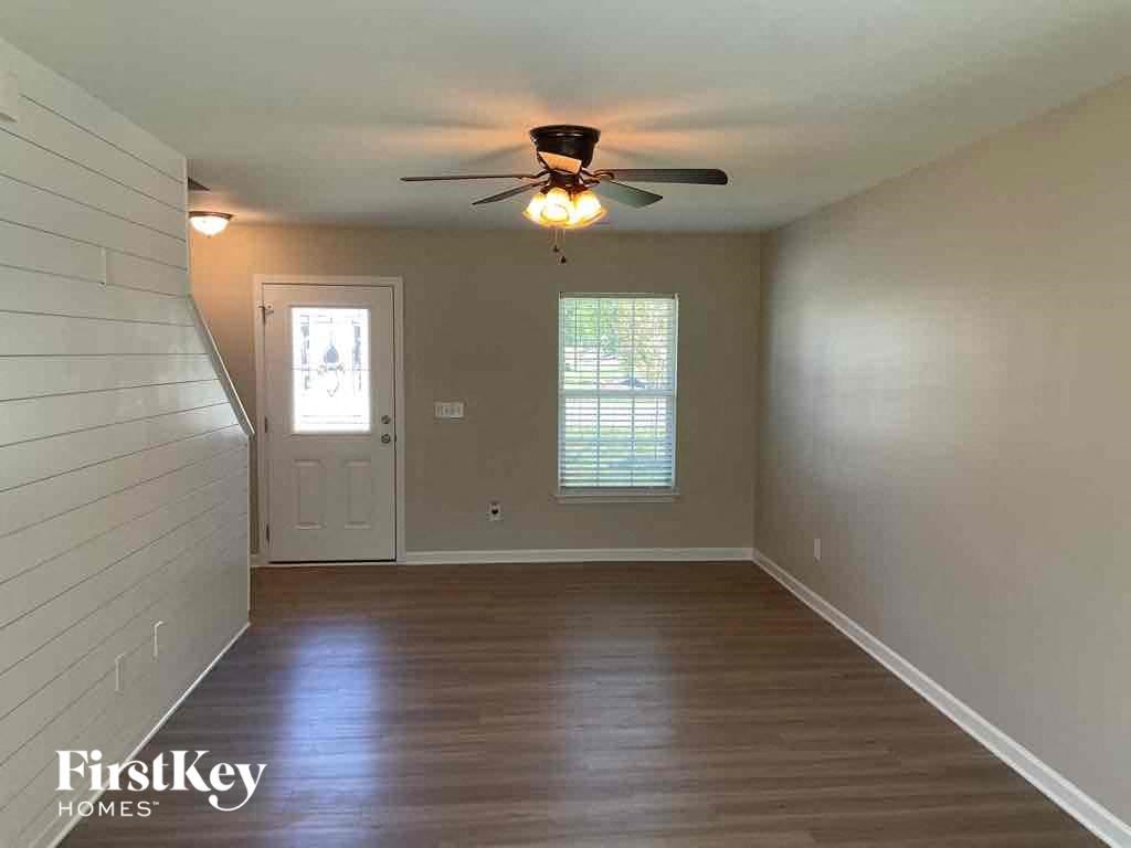 an empty living room with a ceiling fan and a door