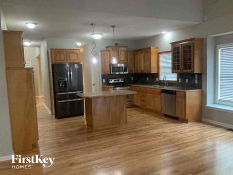 A kitchen with wooden cabinets and a black fridge.