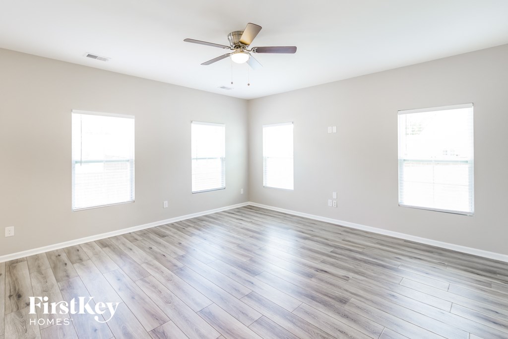 an empty living room with wood floors and a ceiling fan