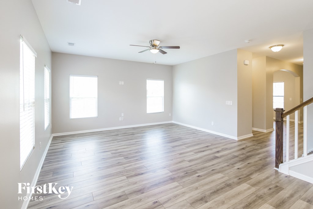 an empty living room with wood floors and a ceiling fan