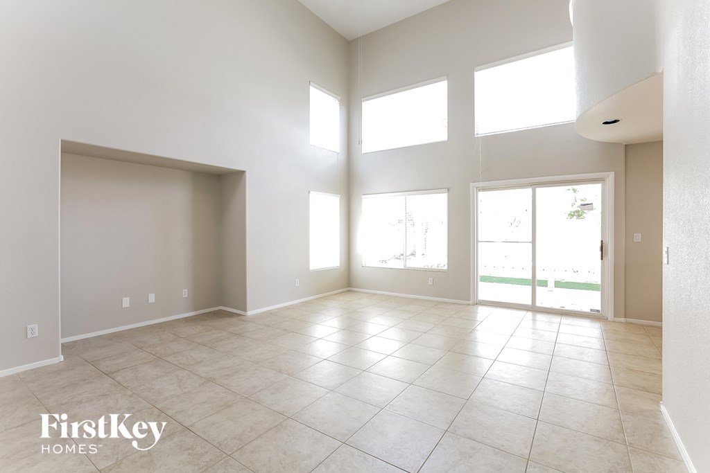 an empty living room with large windows and tile flooring