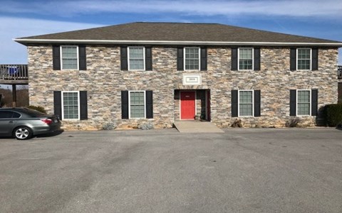 A stone building with a red door and windows.