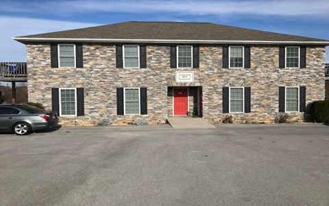 a large brick house with a red door and a parking lot