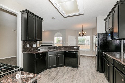 a kitchen with black cabinets and marble counter tops