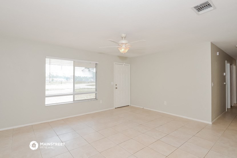 an empty living room with a window and a ceiling fan