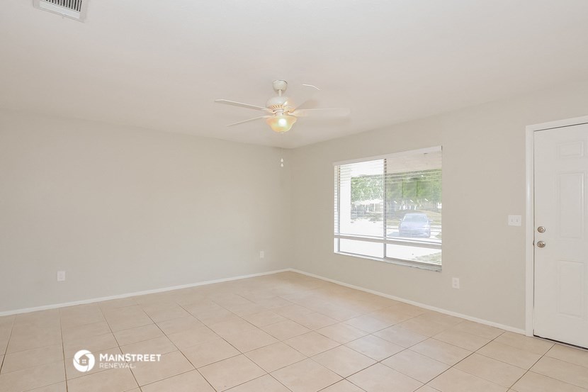 an empty living room with a ceiling fan and a window