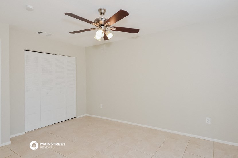 a empty living room with a ceiling fan and a closet