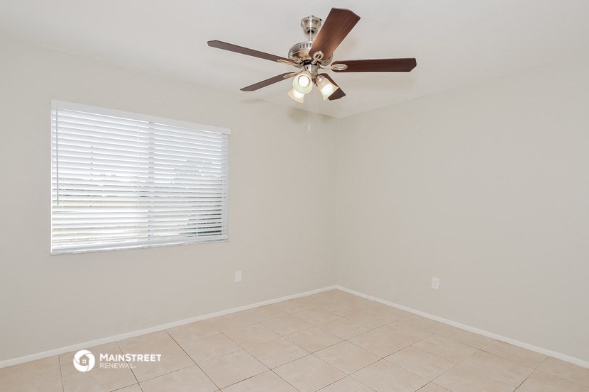an empty room with a ceiling fan and a window