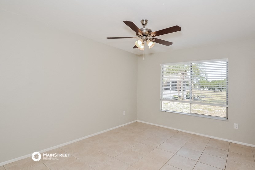 an empty living room with a ceiling fan and a window