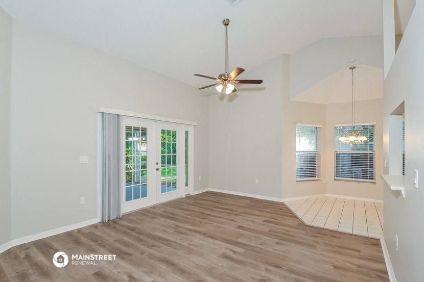 the living room is spacious and has a ceiling fan