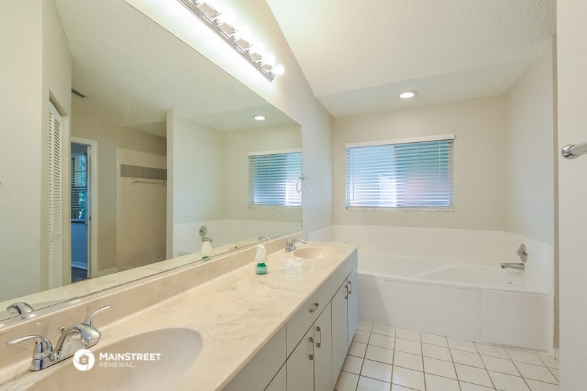 a bathroom with two sinks and a tub and a large mirror
