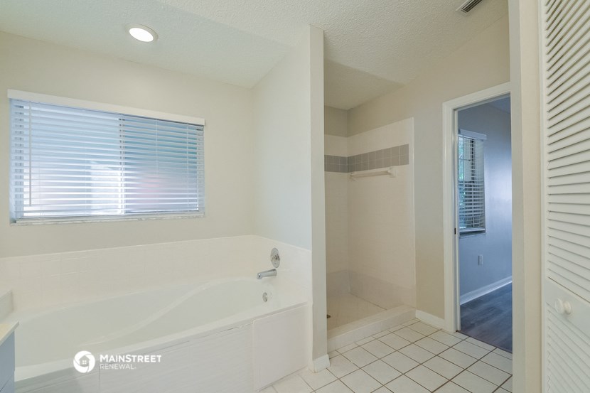 the master bathroom has a large tub and a shower