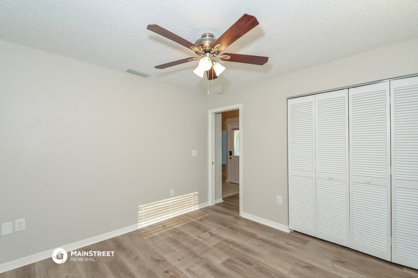 the spacious living room with ceiling fan and closet doors