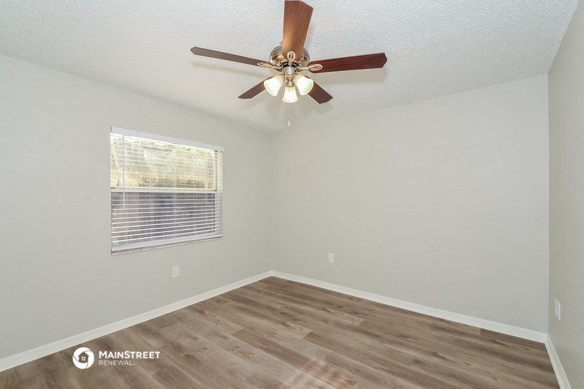 the spacious living room has a ceiling fan and a window