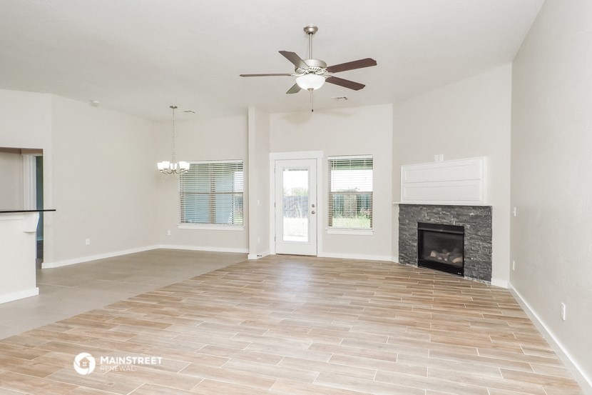 an empty living room with a fireplace and a ceiling fan