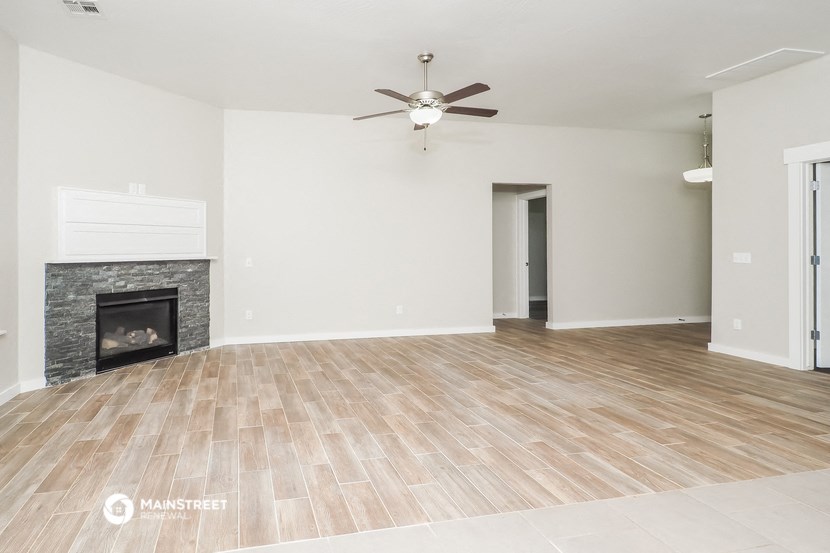 an empty living room with a fireplace and a ceiling fan