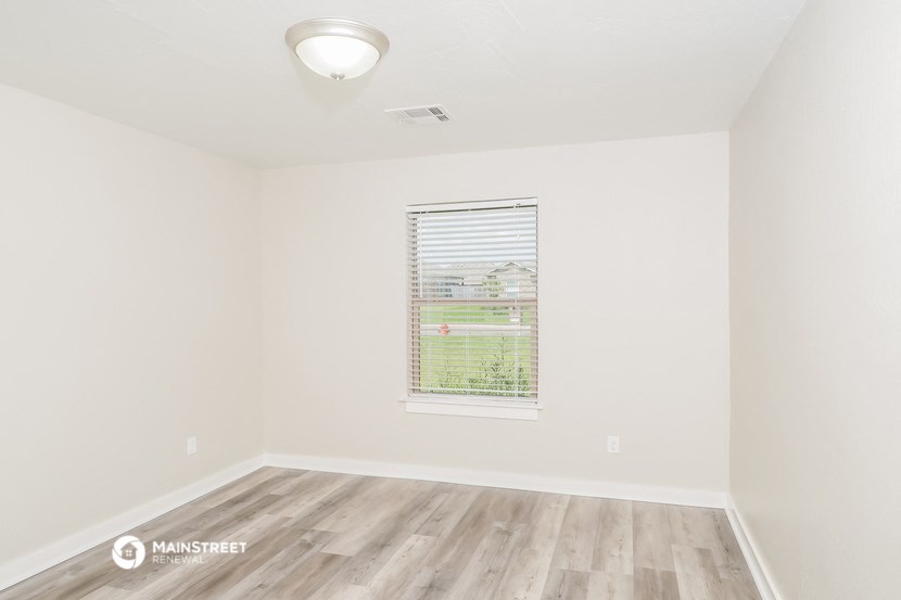 the living room of an apartment with wood flooring and a window