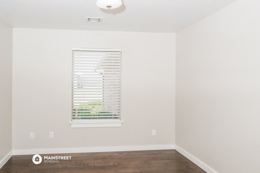 an empty room with a window and a wood floor