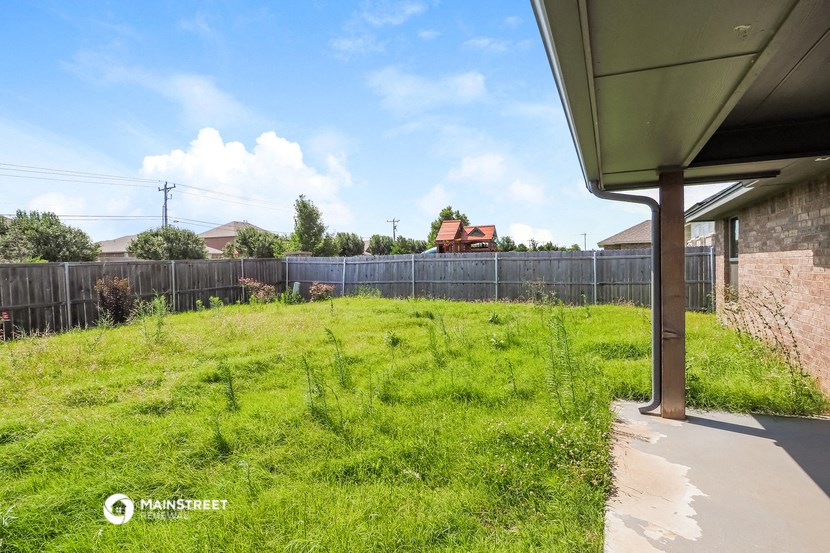 the backyard of a house with a fence and a yard with grass