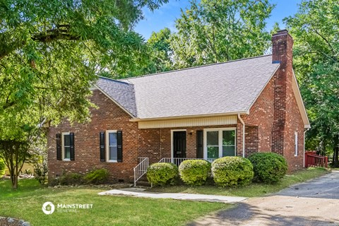 a small brick house with a porch and a tree