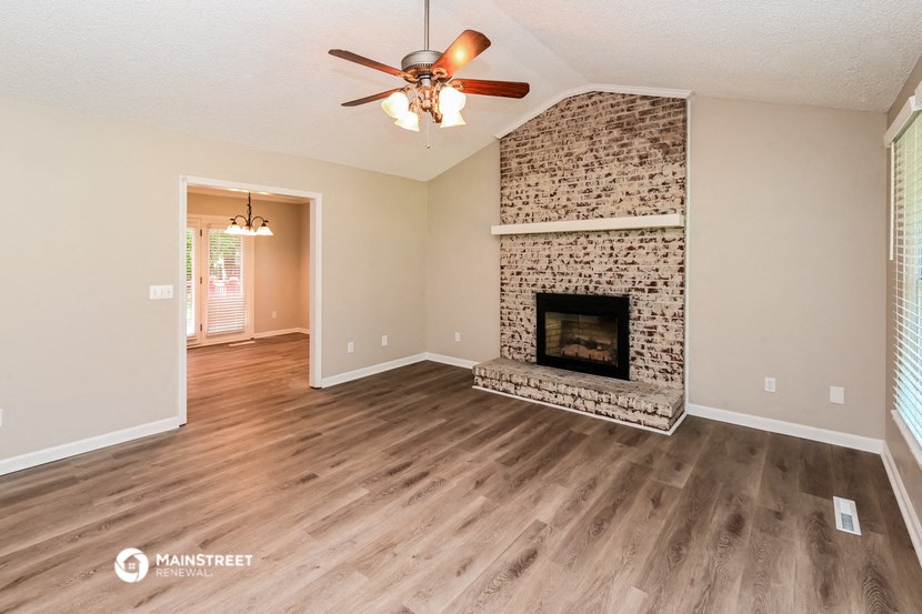 a living room with a fireplace and a ceiling fan